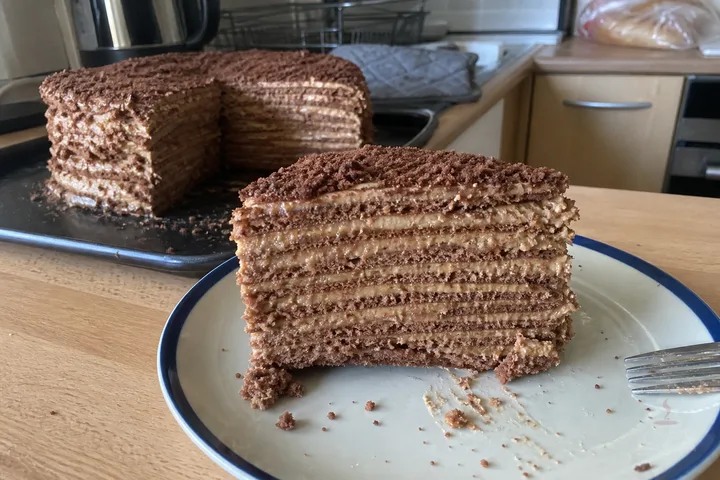 Tall slice of Armenian Mikado cake with many thin caramel cream layers and chocolate