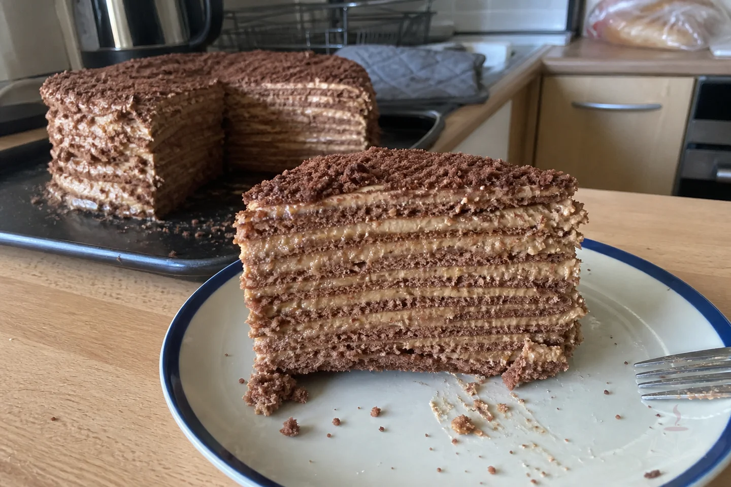 Tall slice of Armenian Mikado cake with many thin caramel cream layers and chocolate