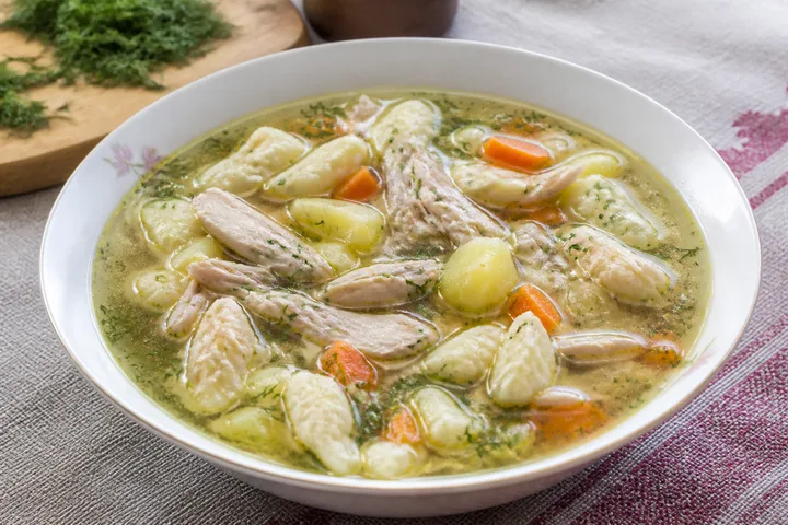Belarusian chicken soup with small flour dumplings, carrots, and fresh dill
