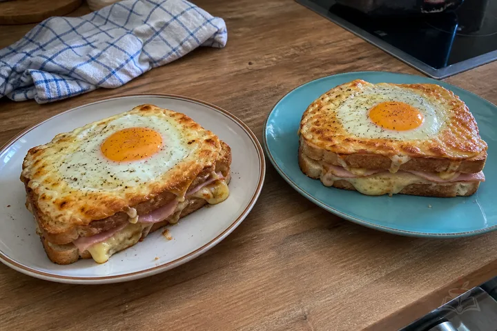 Two French croque madame sandwiches with Gruyère, béchamel, fried eggs, and salad