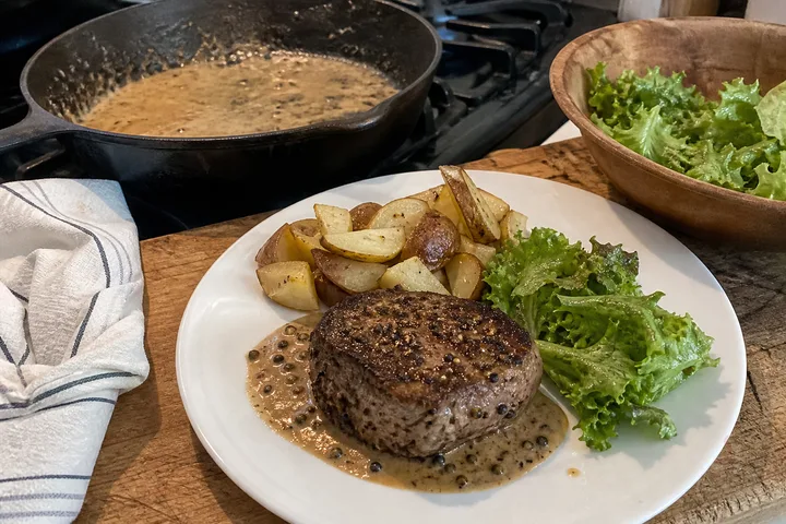 French steak au poivre with peppercorn cream sauce, roasted potatoes, and green salad