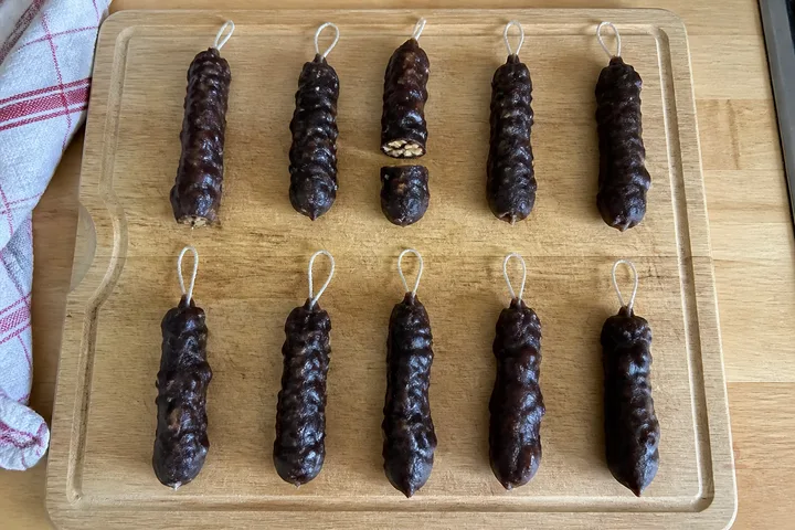 Traditional Georgian walnut churchkhela hanging with cut pieces beside walnuts and grapes