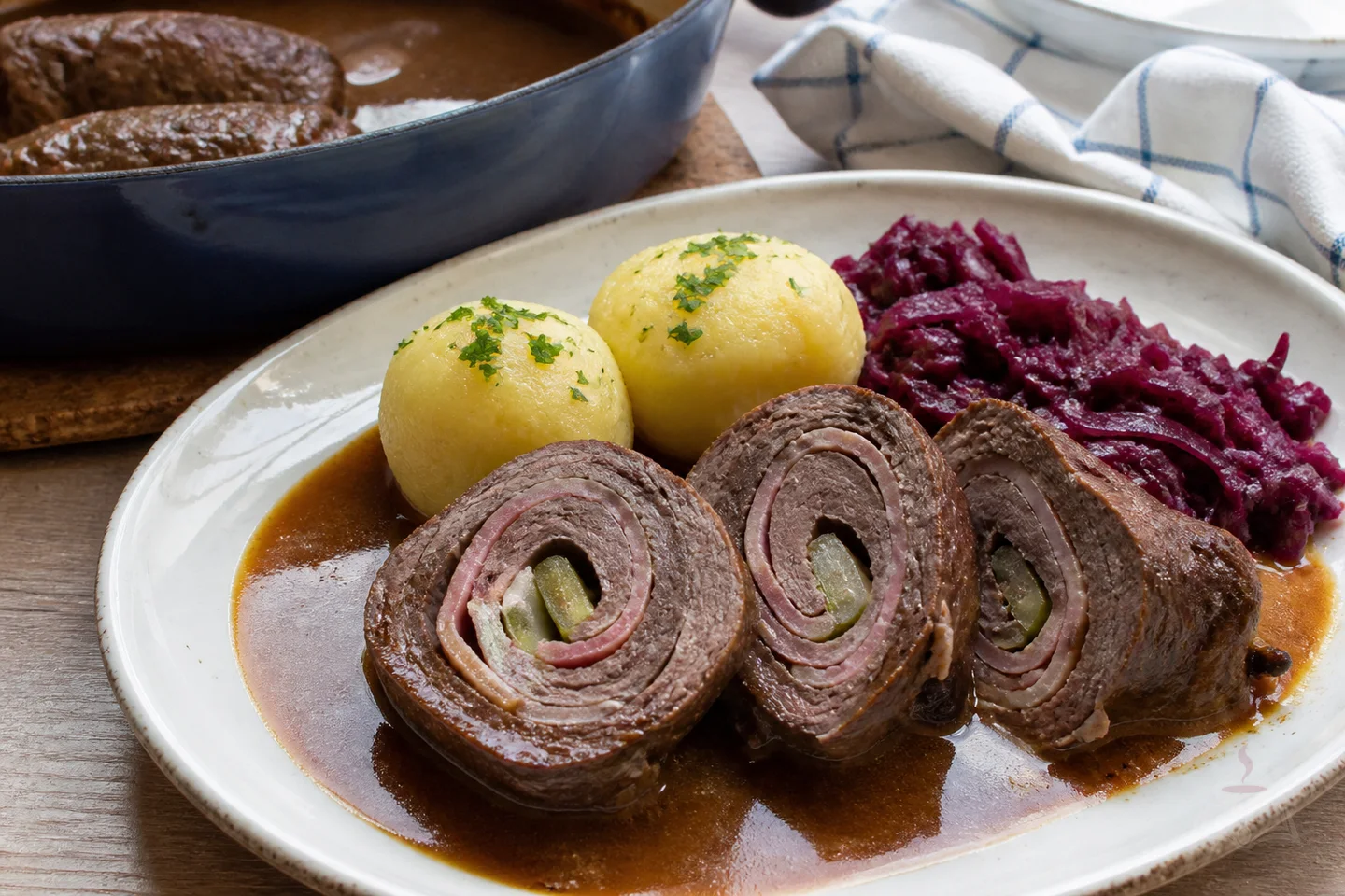 Sliced German beef rouladen with gravy, red cabbage, and potatoes
