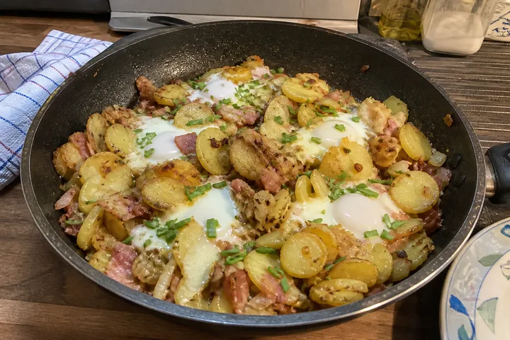 German farmer’s breakfast skillet with potatoes, bacon, onions, eggs, and chives