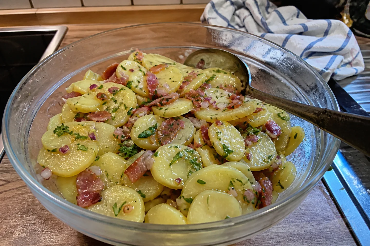 Warm German potato salad with bacon, red onion, mustard dressing, and herbs