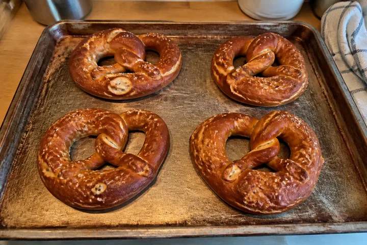 Four German soft pretzels with glossy brown crusts and coarse salt