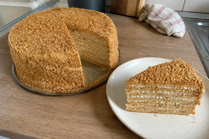 Layered Russian medovik cake with honey crumbs and a cut slice