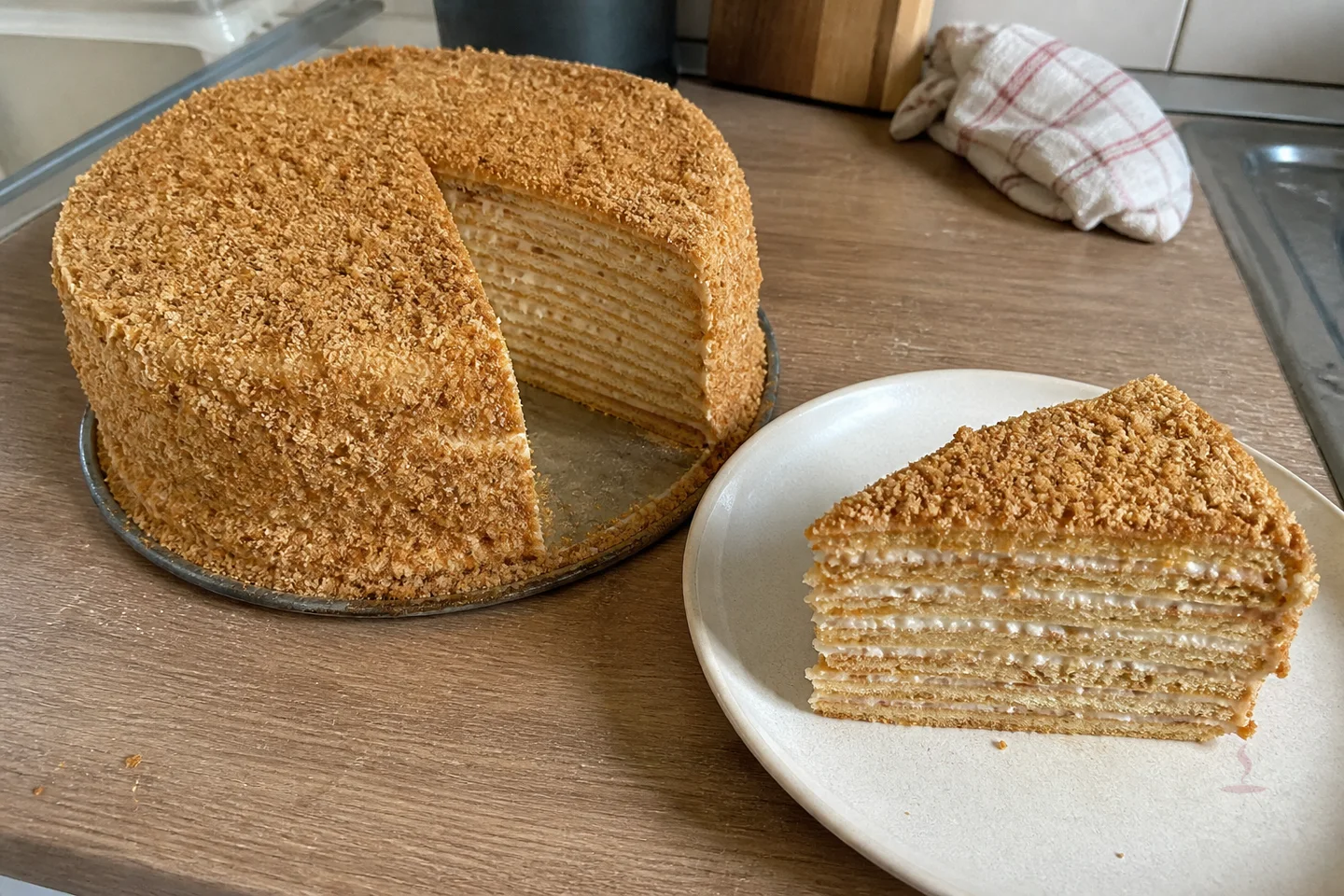 Layered Russian medovik cake with honey crumbs and a cut slice