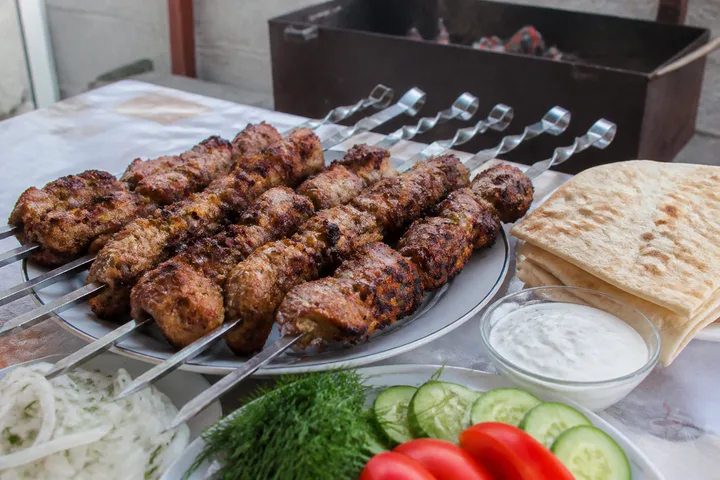 Pork shashlik skewers grilled over glowing coals with onion and dill