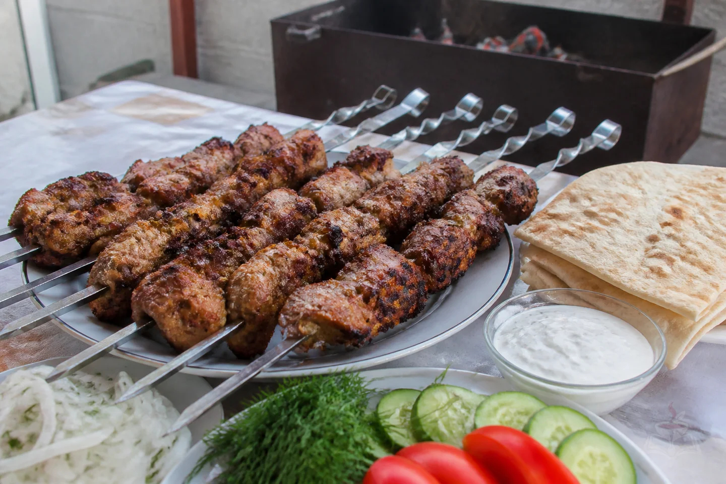 Pork shashlik skewers grilled over glowing coals with onion and dill