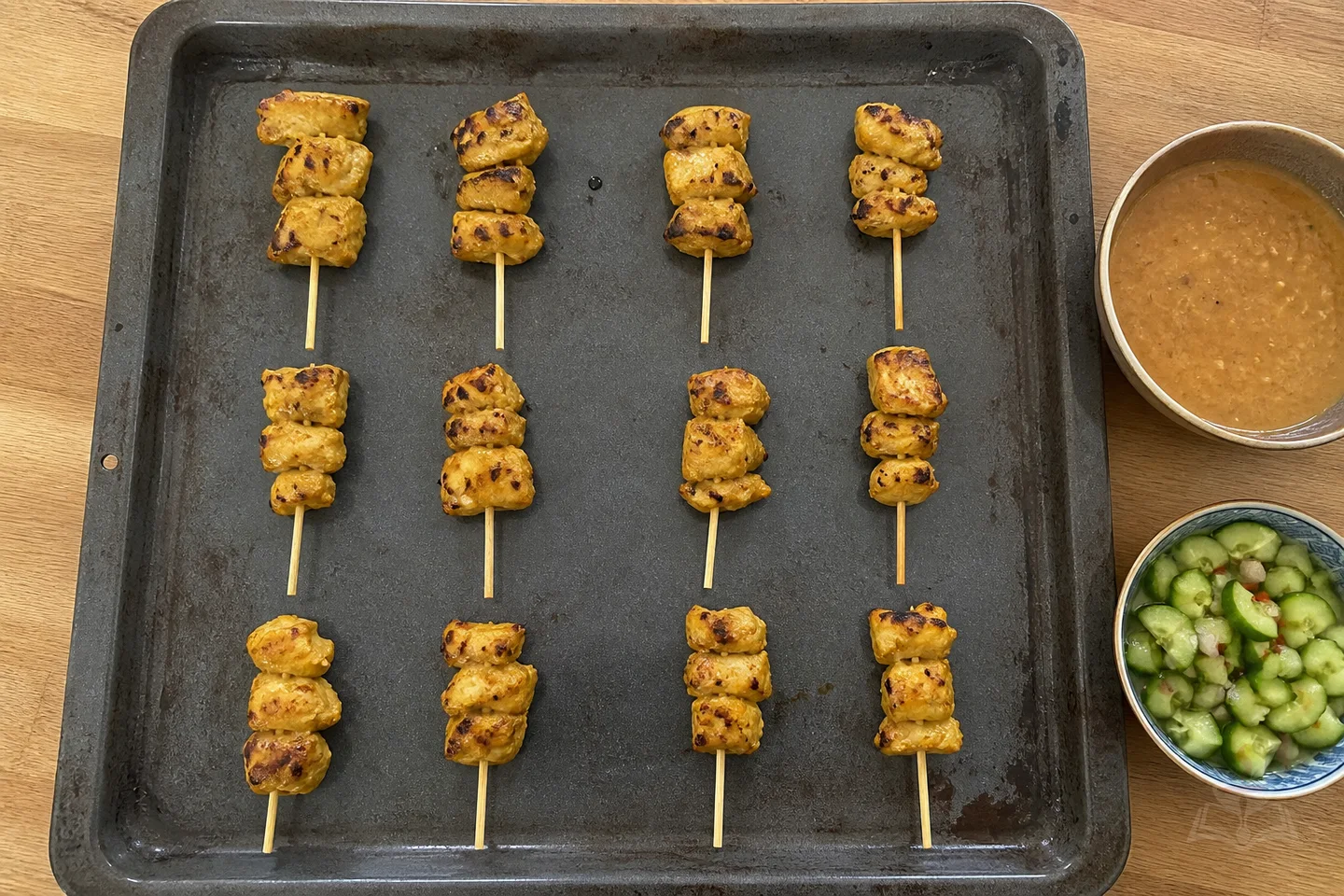 Twelve Thai chicken satay skewers with peanut sauce and cucumber relish