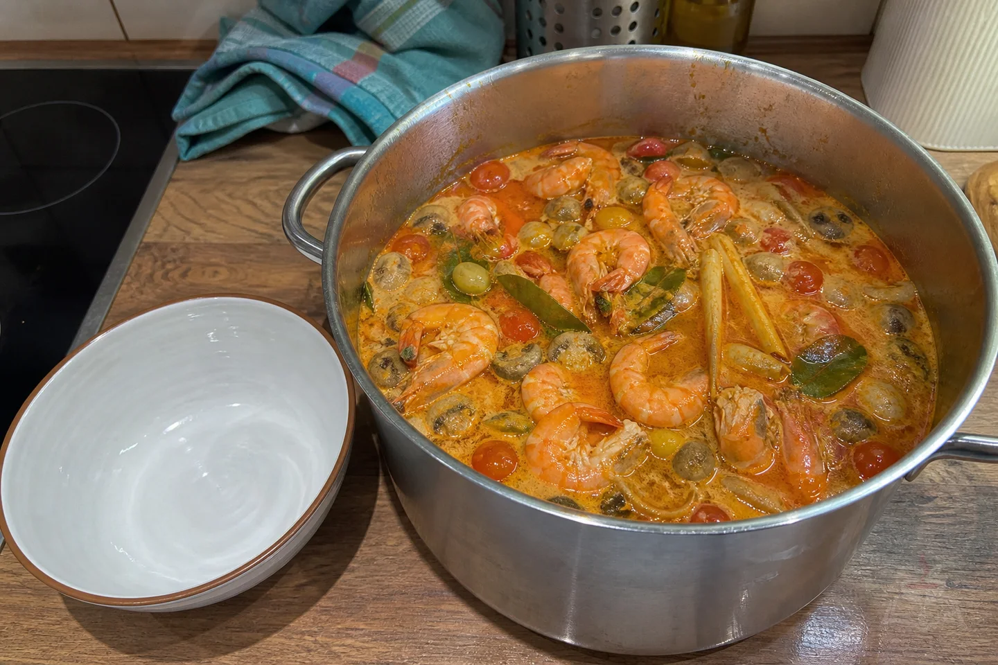 Thai tom yum goong soup with shrimp, mushrooms, lemongrass, lime leaves, and tomatoes
