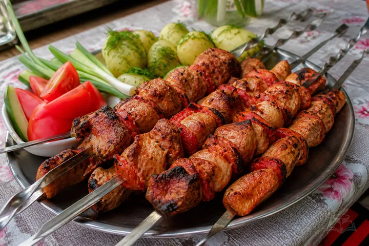 Tomato-marinated chicken shashlik grilling over charcoal with dill and garlic